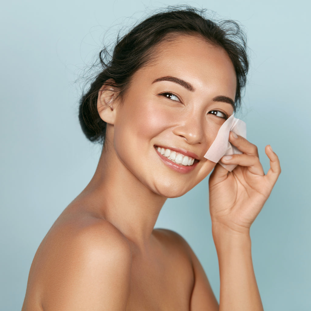 Asian woman using a blotting paper on her face