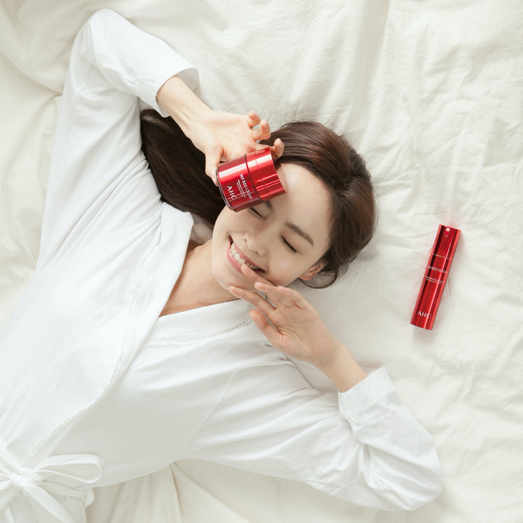 asian woman laying on the bed with AHC products